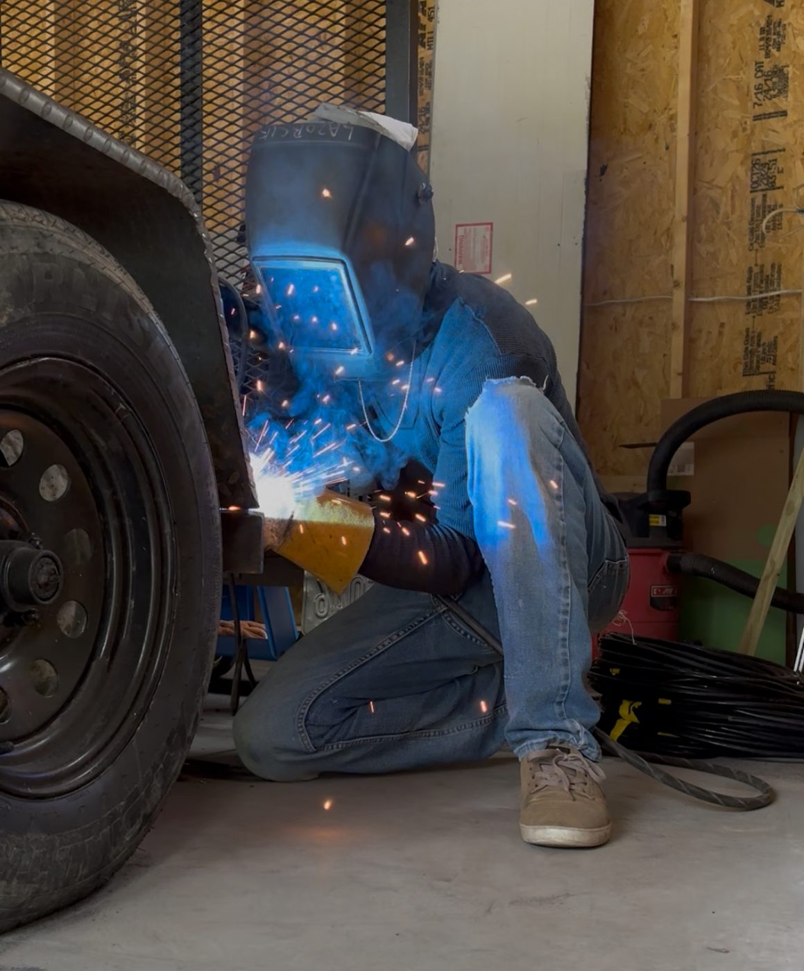 Owner welding under a vehicle with sparks flying